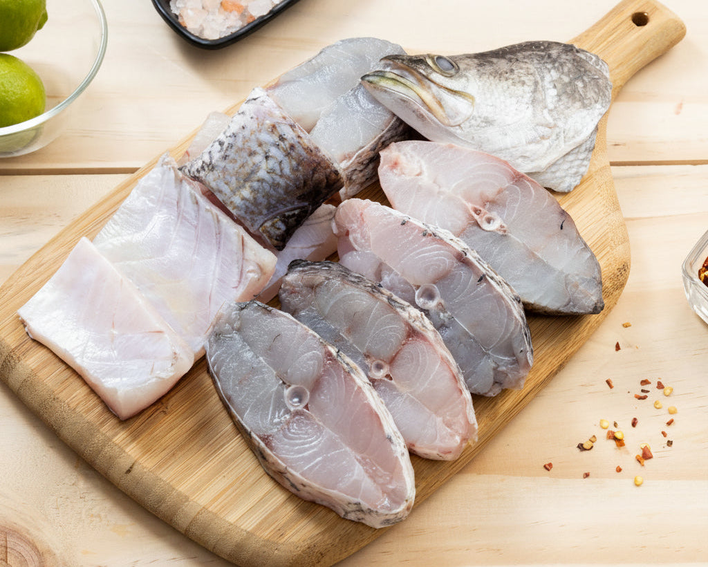 Raw fish fillets on a wooden cutting board with limes and spices in the background.